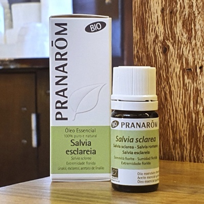 Frasco pequeno de óleo essencial Pranarôm Salvia esclareia com caixa branca e verde sobre mesa de madeira