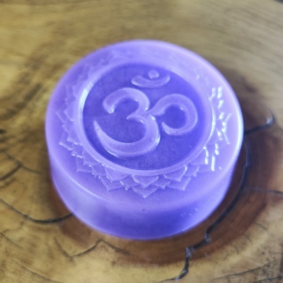 Sabonete roxo com símbolo Om em relevo sobre madeira