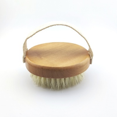 Escova redonda de madeira clara com cerdas brancas e alça de tecido