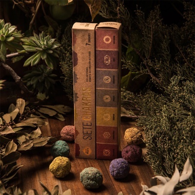 Embalagem Siete Chakras com sete esferas coloridas sobre madeira com plantas secas ao redor