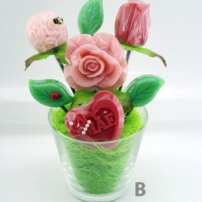 Arranjo decorativo de flores de cera rosa com folhas verdes e coração vermelho com palavra 'MÃE' em vaso transparente
