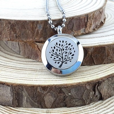 Colar de pendente de árvore em metal prateado com corrente de bolinhas sobre madeira em camadas