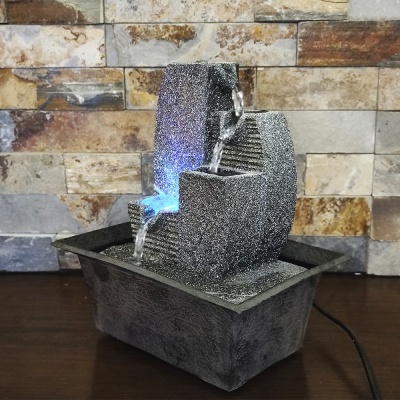 Fonte decorativa em pedra cinzenta com três níveis e luz azul