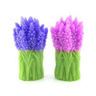 Duas velas decorativas em forma de flores coloridas com base verde