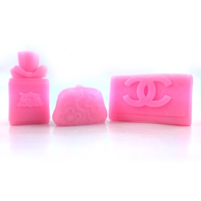 Três sabonetes cor-de-rosa em formas de perfume, mala e carteira