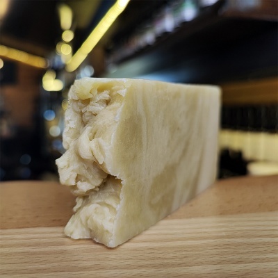 Barra de sabão artesanal bege claro sobre madeira clara