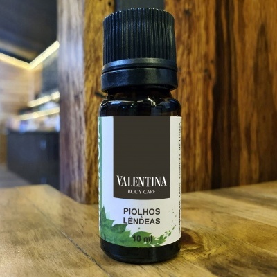 Frasco pequeno de óleo VALENTINA BODY CARE para piolhos e lêndeas sobre mesa de madeira