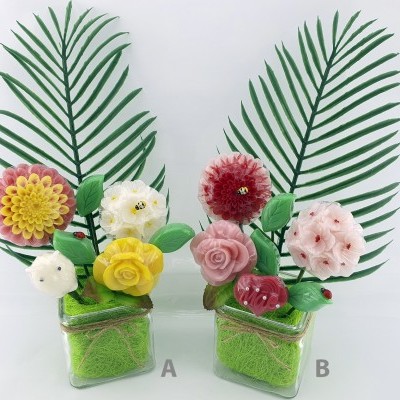 Dois arranjos decorativos com flores coloridas em vasos quadrados transparentes com musgo verde