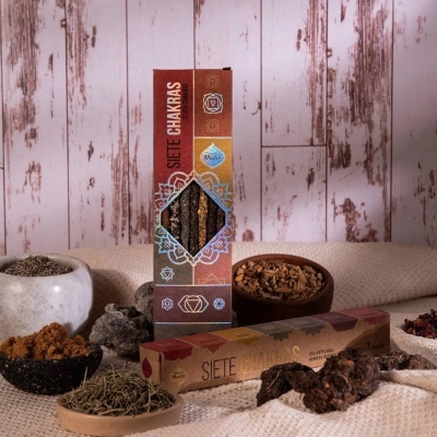 Pacote de incenso Siete Chakras com ervas e resinas em recipientes sobre superfície têxtil clara
