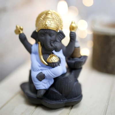 Estatua de Ganesh preta com detalhes dourados e roupa azul em superfície clara