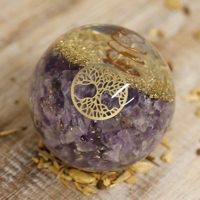 Orbe de resina transparente com pedras roxas e símbolo dourado de árvore da vida sobre madeira