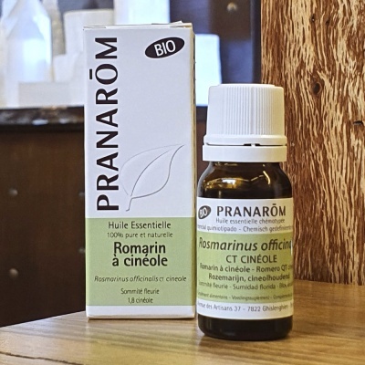 Frasco de óleo essencial Pranarôm e sua embalagem sobre superfície de madeira