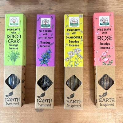 Quatro caixas coloridas de incenso Earth Inspired Smudge Incense com Palo Santo apresentadas lado a lado sobre uma superfície de madeira