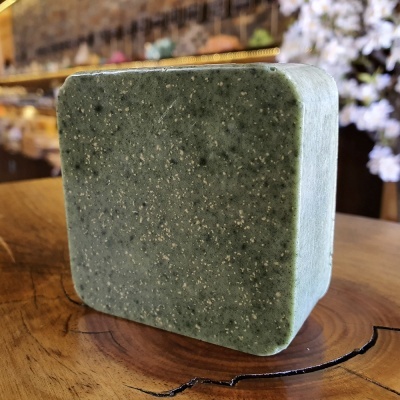 Sabonete quadrado verde escuro com textura sobre superfície de madeira