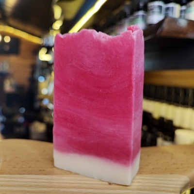 Barra de sabonete artesanal rosa e branca sobre tábua de madeira