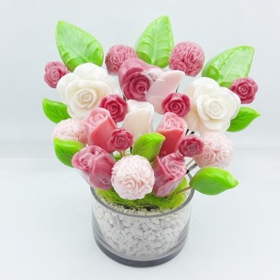 Arranjo decorativo de flores em vaso transparente com pedrinhas.