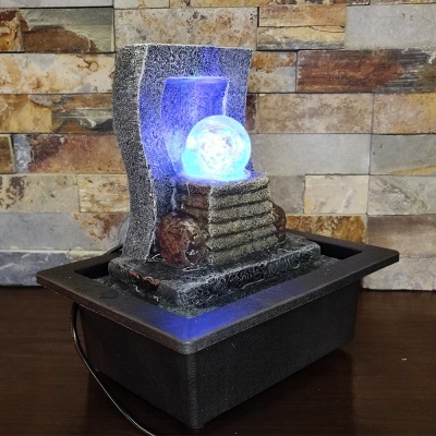 Fonte decorativa com esfera luminosa azul em pedestal de pedra artificial cinza