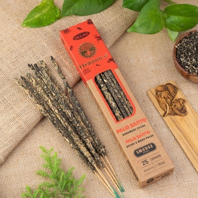 Palitos de incenso Palo Santo em embalagem e folhas verdes sobre tecido rústico