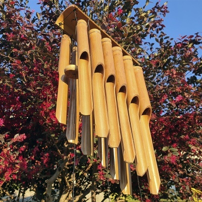 Sino dos ventos de bambu e metal pendurado com fundo de árvores e céu azul