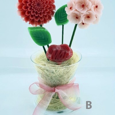 Arranjo decorativo com flores vermelhas e rosa em copo de vidro com laço rosa