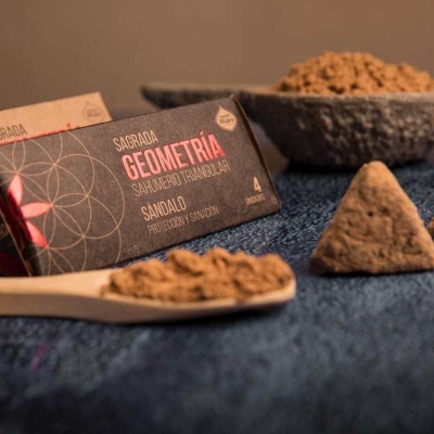 Caixa de incenso geométrico triangular sândalo com pó castanho em colher e tigela sobre tecido azul