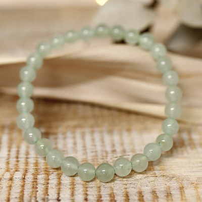 Pulseira de esferas verdes translúcidas sobre madeira clara