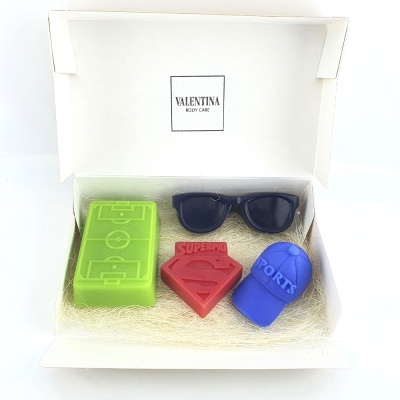 Caixa branca aberta com 3 sabonetes coloridos e óculos de sol