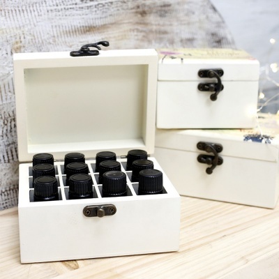 Caixas de madeira brancas com frascos pequenos em uma sobre mesa de madeira clara