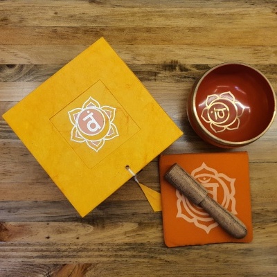 Conjunto de meditação com tigela cerâmica vermelha, almofada laranja e martelo de madeira