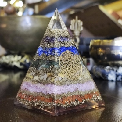 Pirâmide colorida em camadas de pedras e metais com Flor da Vida dourada embutida