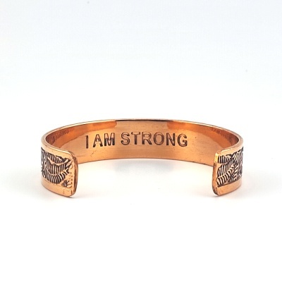 Pulseira de cobre com gravação I AM STRONG e folhas gravadas nas extremidades.