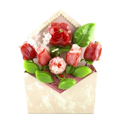 Arranjo decorativo em envelope bege com flores vermelhas e rosa, folhas verdes e abelhas decorativas