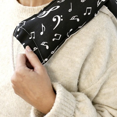 Pessoa com almofada preta com notas musicais brancas sobre suéter bege