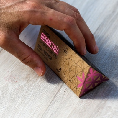 Embalagem triangular de papel castanho com padrões geométricos rosa e preto e texto GEOMETRIA