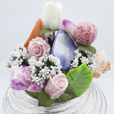 Arranjo de flores artificiais coloridas com folhas verdes sobre base branca