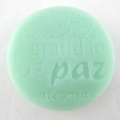 Sabonete verde claro redondo com palavras em relevo sobre fundo branco