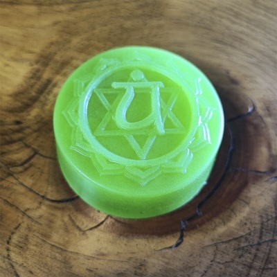 Sabonete verde redondo com símbolo místico em relevo sobre superfície de madeira