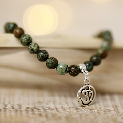 Pulseira com contas verdes e pendente prateado com símbolo