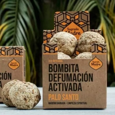 Caixa de cartão reciclado aberta com bolas esferoidais claras e rugosas chamadas Bombita Defumación Activada Palo Santo