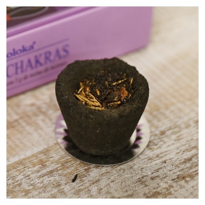 cone de incenso preto sobre suporte metálico com caixa rosa ao fundo