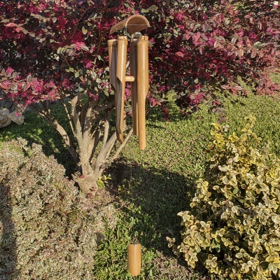 Sino dos ventos de madeira pendurado em árvore com folhas roxas