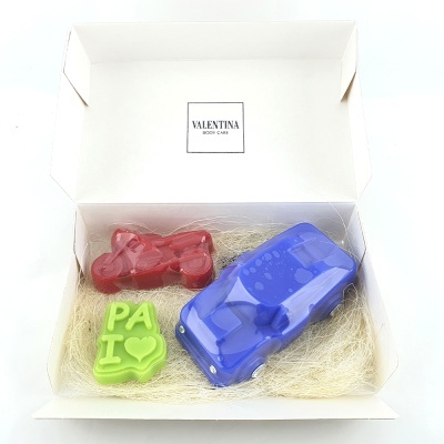 Caixa branca aberta com três sabonetes coloridos em forma de mota vermelha, carro azul e texto verde PA I com coração