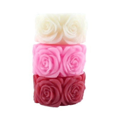 Três velas empilhadas com rosa em relevo nas cores creme, rosa claro e vermelho escuro.