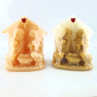 Duas velas decorativas de presépio em tons bege e castanho com figuras religiosas e corações vermelhos no topo.