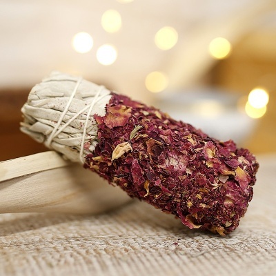 Maço de sálvia branca com pétalas vermelhas secas sobre tecido cinza claro