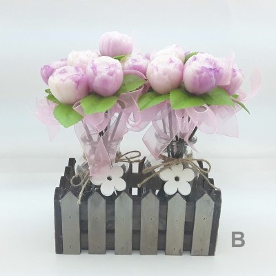 Arranjo decorativo com flores rosa em vasos de vidro dentro de suporte de madeira cinzenta