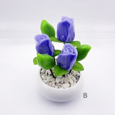 Vaso pequeno branco com flores artificiais roxas e folhas verdes