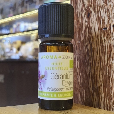 Frasco de óleo essencial de Géranium Egypte Aroma-Zone sobre mesa de madeira com fundo desfocado