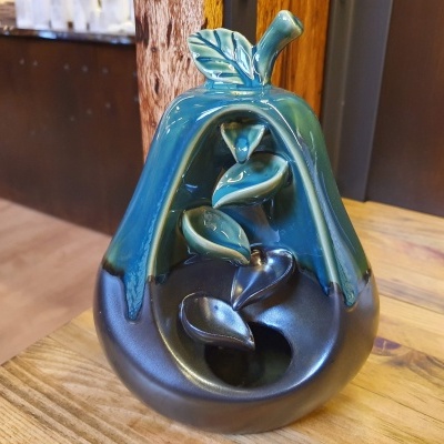 Vaso de cerâmica em forma de pêra verde e preta sobre superfície de madeira