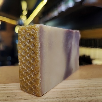 Sabonete artesanal bicolor com textura hexagonal numa extremidade sobre madeira